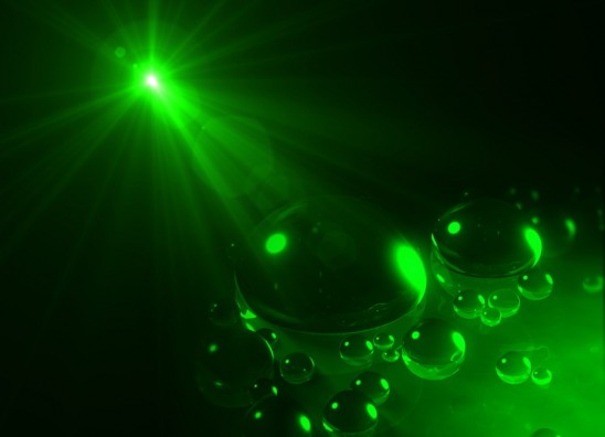 Illustration of a light beam attracting oil drops on the surface of water