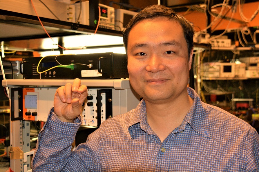 Dr. Yong Yang holding the near-invisible micro-bubble resonator mounted on a small glass microscope slide