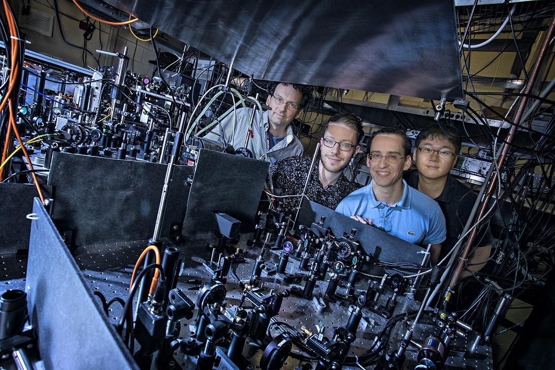 Professor Schneble, far left, with PhD students Michael Stewart, Ludwig Krinner, and Joonhyuk Kwon, assemble around the large atom trap system created in their Stony Brook lab.
