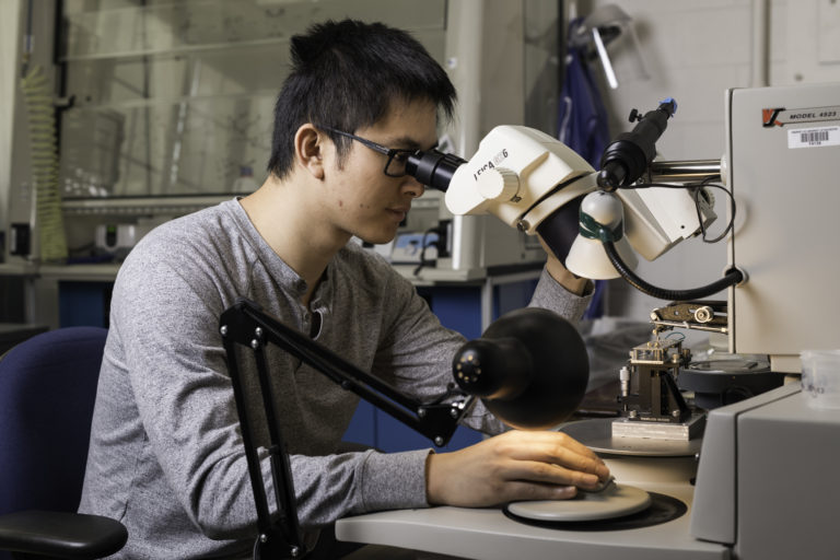 Doctoral student Haifeng Qiao uses a wire bonder to make electrical contact between the circuit board and the experimental device.