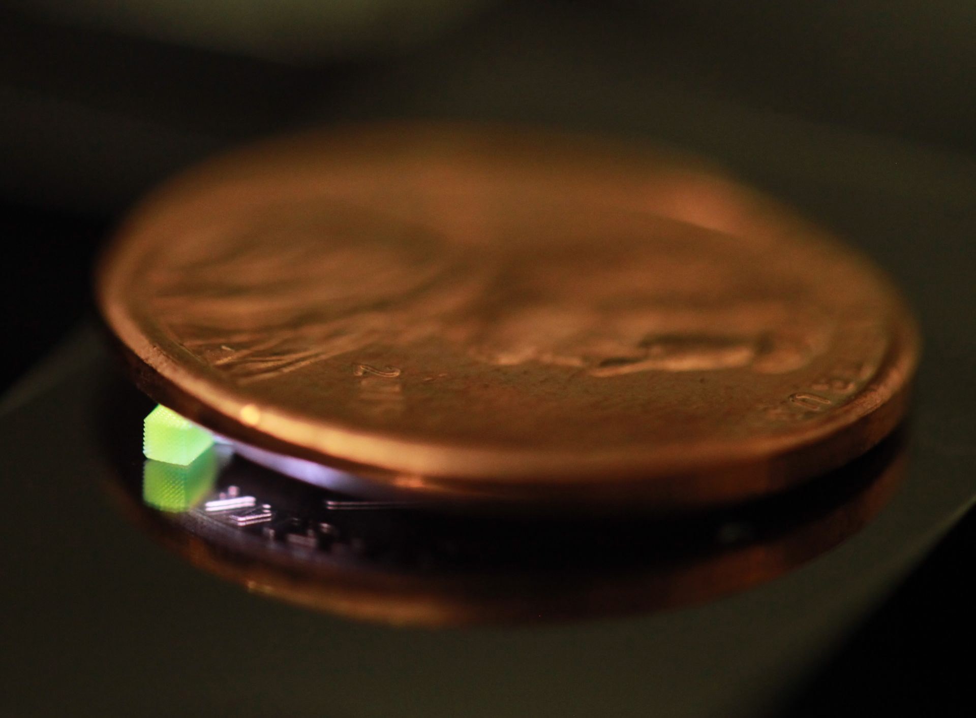A millimeter-scale structure with submicron features is supported on a U.S. penny on top of a reflective surface