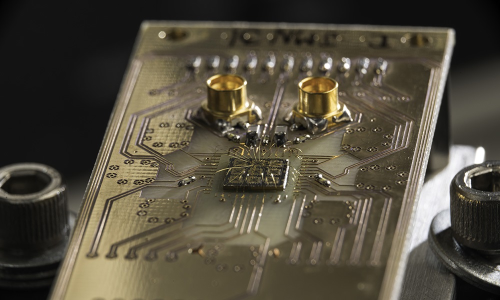 A quantum processor semiconductor chip is shown connected to a circuit board