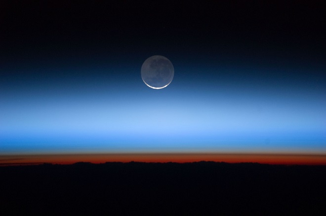 The sun is just below the horizon in this photo and creates an orange-red glow above the Earth’s surface