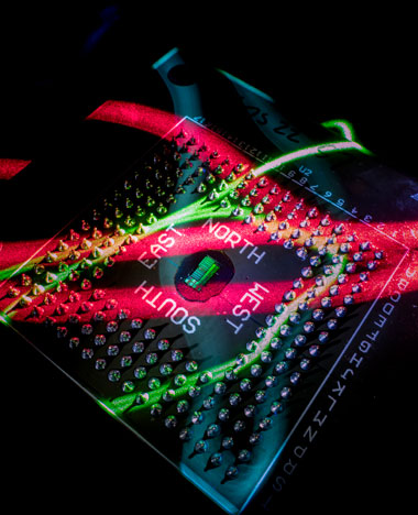 The electronic-photonic processor chip naturally illuminated by red and green bands of light