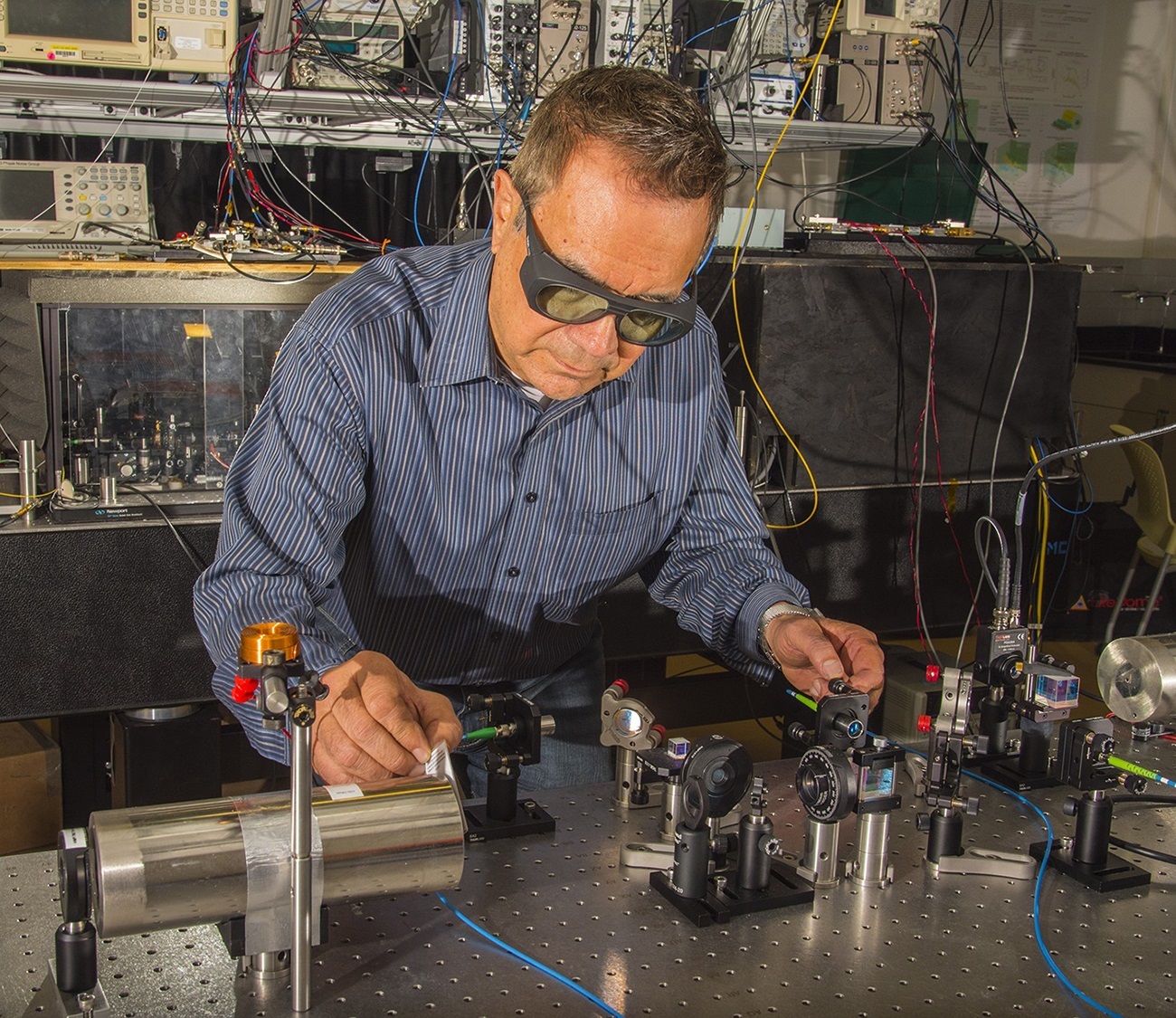 NIST physicist Dave Howe aligns a laser beam to pass through a tiny glass cell of rubidium atoms inside the cylindrical magnetic shield