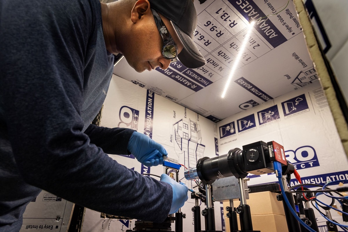 Raju Lampande, postdoctoral researcher in Giebink’s lab, positions an OLED that leverages positive feedback to amplify the conversion of near infrared light into visible light in front of a microscope imaging system