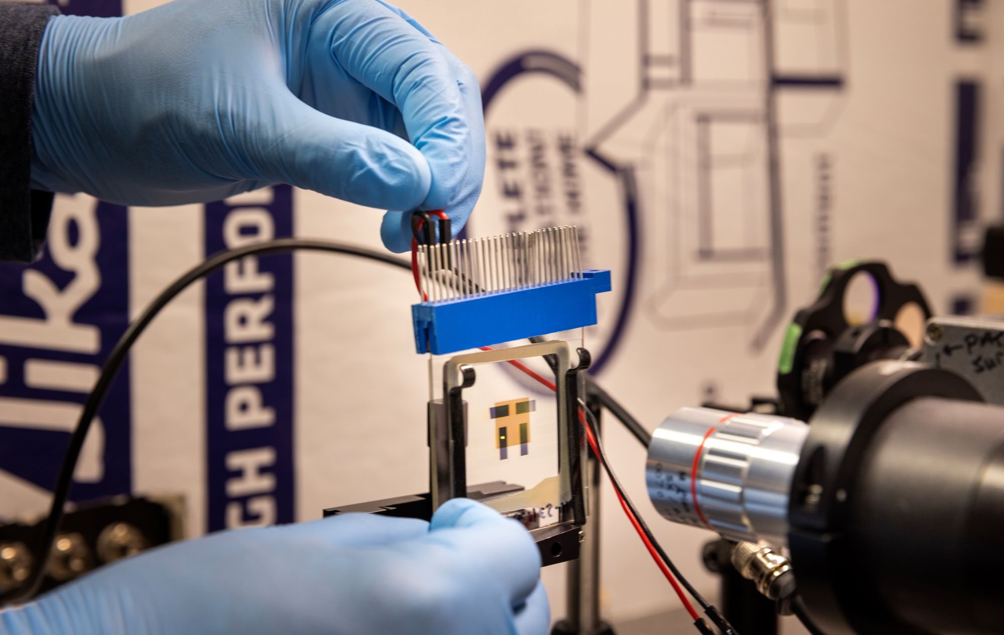 Raju Lampande, postdoctoral researcher in Giebink’s lab, positions an OLED that leverages positive feedback to amplify the conversion of near infrared light into visible light in front of a microscope imaging system