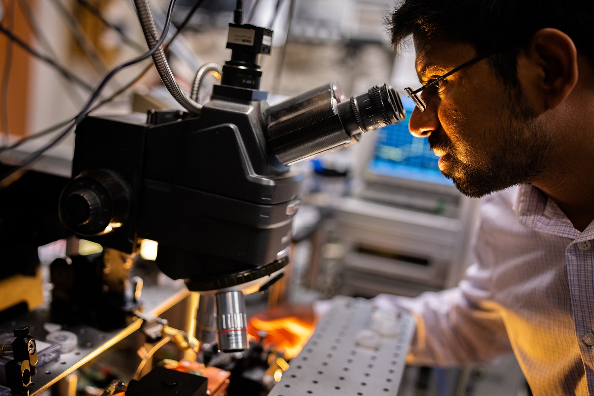 Sandia National Laboratories scientist Ashok Kodigala aligns a fiber to a chip-scale, heterogeneously integrated laser under a microscope at the MESA complex
